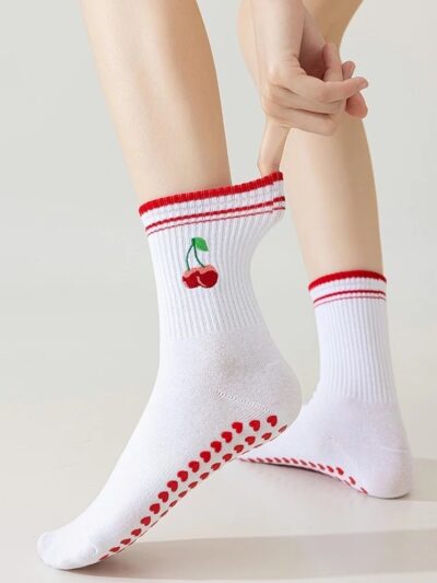 kobieta nosząca retro skarpetki do pilatesu ze wzorem wiśni i trzymająca za ich krawędź