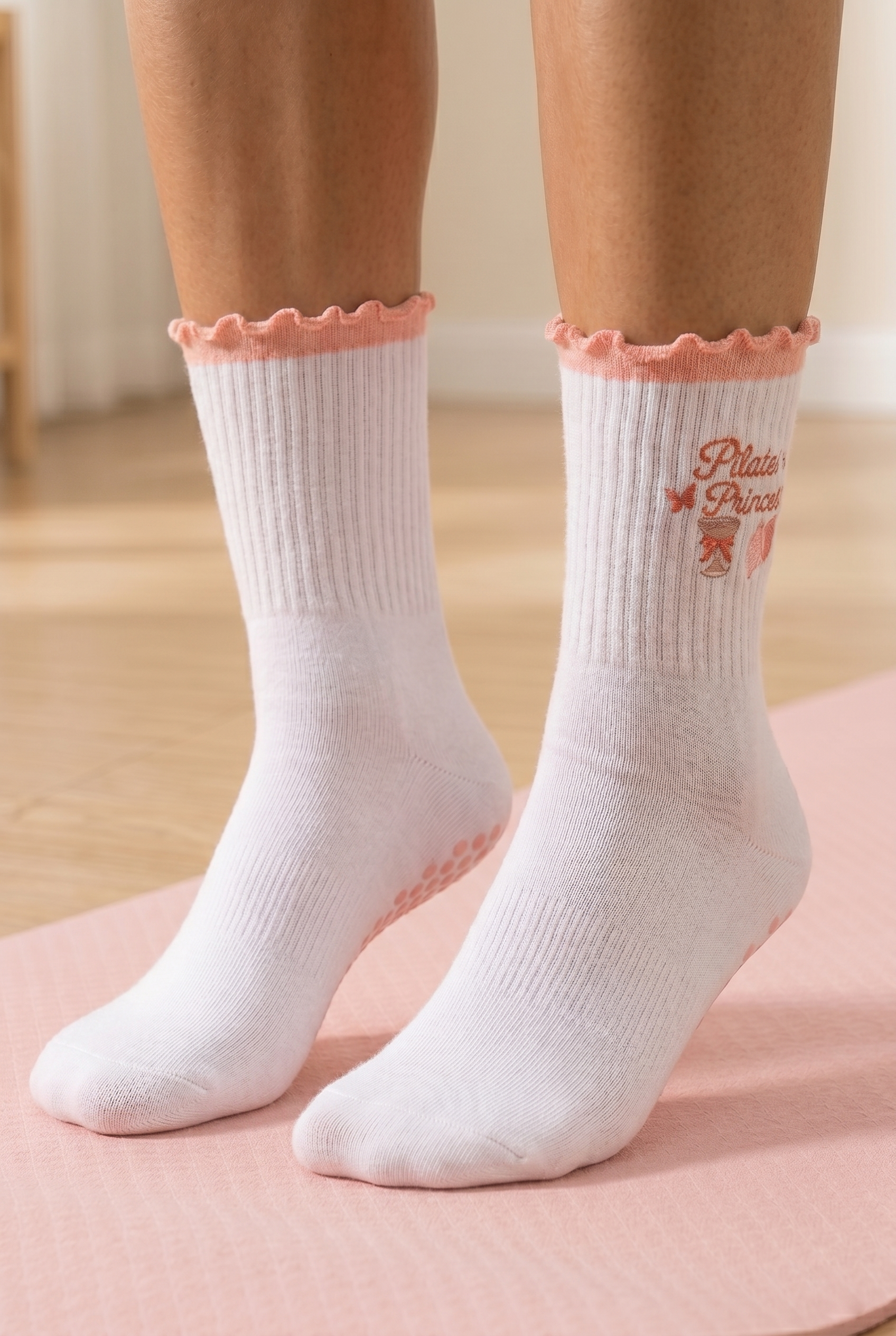 kobieta nosząca białe skarpetki Pilates Princess na różowej macie do ćwiczeń