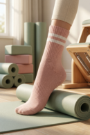 różowe skarpetki do pilatesu na stopach modelki, zielone i różowe akcesoria do pilatesu w tle